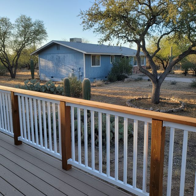A deck railing with white balusters and a stained wood top rail